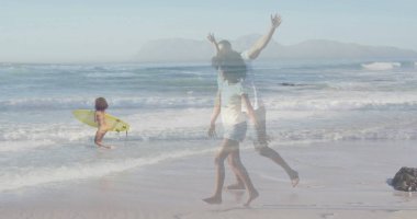 Yürüyen ebeveynler, sarı sörf tahtası taşıyan çocukla kumlu sahil şeridinde kollarını kaldırıyorlar. Deniz kenarı, aile hayatı, macera, yaz, boş zaman, açık hava, mutluluk