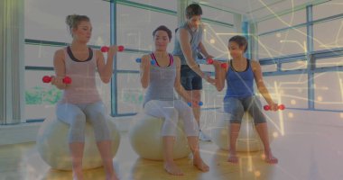 Stüdyoda dengeli topların üzerinde duran dambıllar kullanarak, spor eğitmeninin rehberliğinde bisepsleri kıvırarak kadınlar yapıyor. Sağlık, fitness, antrenman, spor, egzersiz, sağlık, motivasyon