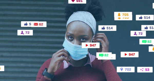 Woman in sweater adjusting surgical mask straps on sidewalk, with smartwatch, social media icons. Urban, lifestyle, minimalism, technology, communication, casual, empowerment