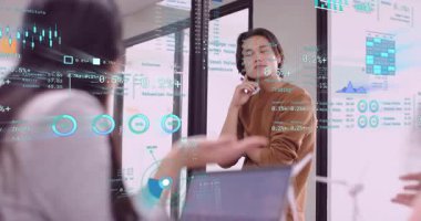 İş arkadaşı jestine tepki veren mali analist, cam tahtadaki tabloların altını çiziyor. Şirket, işbirliği, sunum, analitik, modern, teknoloji, profesyonel