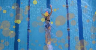 Tepedeki kamera, kadın yüzücüyü, dayanıklılık için spor havuzunda serbest yüzme turları atarken yakalıyor. Atletik, rekabet, hareket, eğitim, spor, su, dinamik