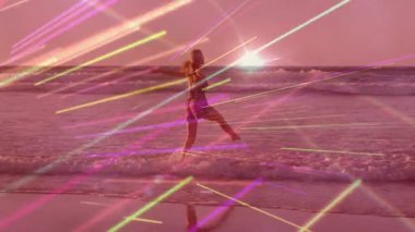 Sörf yapan bir kadın, günbatımı dalgalarının üzerinde hareketli neon çizgiler çizerek teknolojiyi resmediyor. Deniz kıyısı, macera, canlı, dinginlik, hareket, yansıma, fütüristik