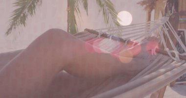 Plajdaki halat hamağında mayo giyen gevşemiş bir kadın. Palmiye ağaçları, karatahta işareti. Tropik, açık hava, dinlenme, dinginlik, bohem, doğal, tatil