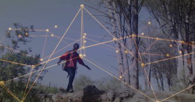 Kırmızı ceketli bir adam orman açıklıklarında düşmüş bir sandıkta dengede duruyor, bir sürü ve parlayan örtüyle. Macera, keşif, canlılık, açık hava, canlı, esneklik, dinginlik