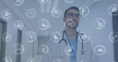 Stetoskop, dijital ikonlar ve kimlik kartıyla hastane koridorunda yürüyen doktor. Tıbbi, sağlık, teknoloji, tanı, profesyonel, gelecekçi, klinik
