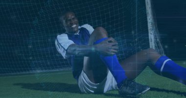 Mavi-beyaz formalı bir diz oyuncusuyla stadyumun suni sahasında oturuyor ve kale ağı kaplamalı. Sporcu, spor, rekabet, esneklik, teknoloji, performans, fitness