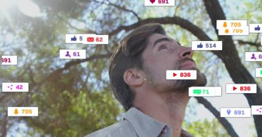Ağaçların altında düğmeli gömlek giyen yetişkin bir adam, yüzen bildirim simgeleriyle. Doğa, teknoloji, dijital, iletişim, açık hava, modern, bağlantı