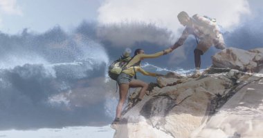 Birbirini destekleyen iki yürüyüşçü çarpışan dalgalar ve sırt çantalarıyla kayalık sahil kayalıklarına tırmanıyor. Macera, keşif, arkadaşlık, dağlar, açık hava, engebeli, serüven