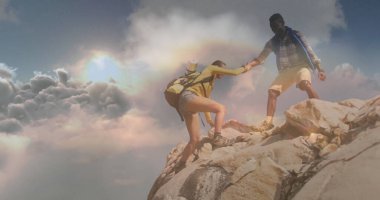 Sırt çantaları ve su şişeleriyle dağ zirvesinde tırmanan çiftler birbirlerine yardım ediyorlar. Macera, takım çalışması, keşif, açık hava, engebeli, manzara, ilham