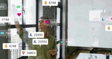 Zeytin gömlekli bir kadın ofisteki cam duvarlara yüzen sosyal medya simgelerini vuruyor, çizimler, kalemler. Modern, profesyonel, minimalist, kentsel, teknolojik, motive edici, yaratıcı