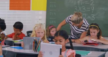 Okulda dijital tabletle çocuklara öğretmenlik yapan bir öğretmen. Eğitim öğrenimi ve teknoloji konsepti dijital olarak oluşturulmuş video.