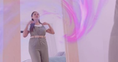 Kadın aynada tulumu düzeltiyor, kumaşı düzleştiriyor ve moda tasarımı için kemeri ayarlıyor. Moda, stil, kostüm, iç mekan, günlük, güven, sağIık.