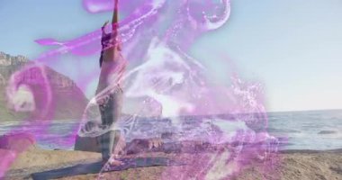 Kadın sağlık koçu kayalık kıyıya geliyor şafak vakti yoga minderini yerleştiriyor esniyor ve yuvarlanıyor. Meditasyon, ahenk, dinginlik, esneklik, açık hava, minimalist, canlılık