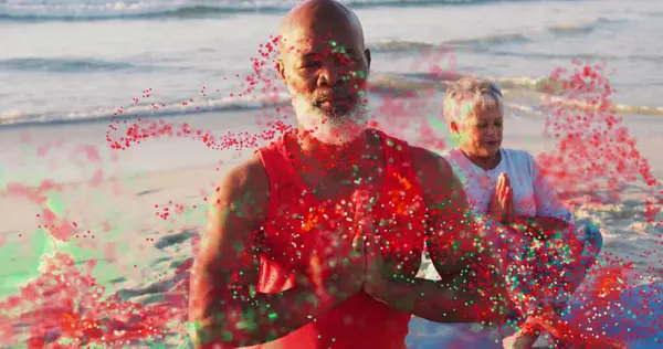 Kırmızı tişörtlü bir adam ve kumsalda dua eden açık tişörtlü bir kadın, yoga partnerleri. Meditasyon, farkındalık, refah, uyum, dinginlik, doğa, rahatlama.