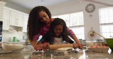 Anne, kizinin rehber mangırlarinin uzerine ellerini koyuyor ve kalinligini gostererek hamuru ceviriyor. Aile, aşçılık, gelenek, akıl hocalığı, el yapımı, yerli, aşçılık