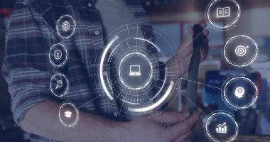 Erkek teknisyen AR kaplamasına başlayan cihazı alıyor, teknoloji atölyesinde test için simgeler seçiyor. Güçlendirilmişlik, yenilik, dijital arayüz, teknoloji, endüstriyel, gelecekçi, eğitim