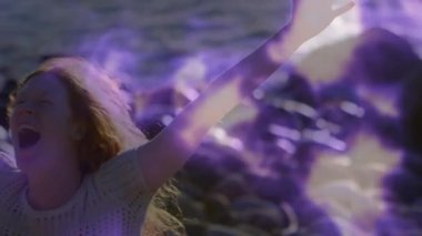 Teknoloji tanıtımı için kayalık kıyı şeridinde dönen mor enerjiyi çağıran bir kadın. Enerjik, güçlü, mistik, canlı, manzaralı, kutlama, fantezi