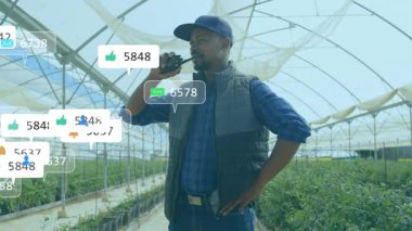 Sera yöneticisi radyoya konuşuyor, bitkileri çevreleyen animasyon simgelerini gösteriyor sonra da soluyor. Tarım, iletişim, teknoloji, üretkenlik, modern, bahçıvanlık, bağlantı