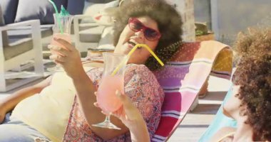 İki arkadaş pembe içecekleri kaldırıyor, avluda kadeh tokuşturup canlandırılmış ikonlar gibi pazarlama yapıyorlar. Sosyalleşme, boş zaman, açık hava, coşku, dostluk, rahatlama, kutlama