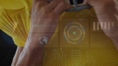 Sporda sarı formada görünen dijital HUD kaplamalarından sonra kask çene kayışını ayarlayan sporcu. Sporcu, spor, dişli, ekipman, yenilik, teknoloji, odaklanma