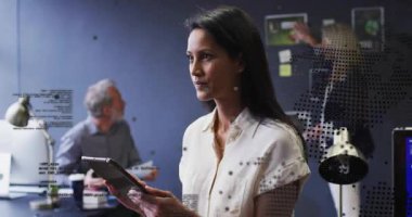 Kadın tablet ekranına dönüyor ve iş planlama için veri kaydırıyor, animasyon çizelgeleri gösteriyor. İşbirliği, takım çalışması, beyin fırtınası, çalışma alanı, ofis, dijital, planlama