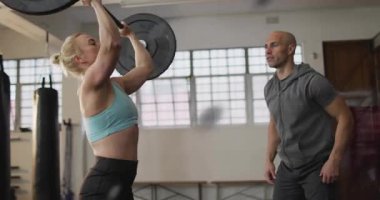 Kadın sporcu, önce halteri temizliyor, sonra spor salonunda antrenör formunu doldururken kafa üstü asılıyor. Fitness, strength, training, yetkilendirme, kararlılık, spor, atletizm