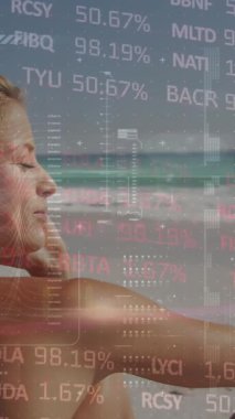 Animation of financial data processing over woman on beach. Global holiday, finance, computing, connections and data processing concept digitally generated video.
