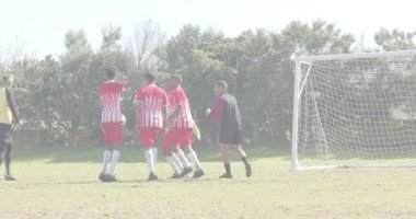 Futbol savunmacıları duvar oluşturuyorlar ve kaleci topu alırken serbest vuruşu engellemek için zıplıyorlar. Sporcular, takım çalışması, spor, aksiyon, rekabet, açık hava, canlı