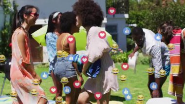 Sosyal medya tepkisi simgeleri gökyüzüne doğru sürüklenirken arkadaşlar arka bahçeye gelip birbirlerini selamlıyorlar. Yaşam tarzı, açık hava, kutlama, eğlence, canlı, neşeli, sıradan