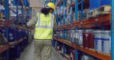 Neon yelek giyen bir kadın, depo envanterini güncellerken kutuları üst üste yığıyor. Sanayi, lojistik, otomasyon, verimlilik, teknoloji, organizasyon, üretkenlik