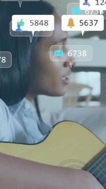 Kanepede gitar çalan kadın üzerine medya simgeleri. Sosyal medya, yaşam tarzı ve dijital arayüz konsepti dijital olarak oluşturulmuş video.