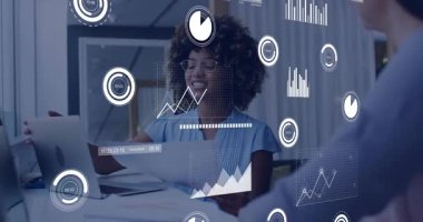 Kadın, ofisteki meslektaşına holografik çizelgeleri gösterirken rapor veriyor ve el kol hareketi yapıyor. Futuristik, işbirliği, veri görselleştirme, teknoloji, yenilik, profesyonel, dijital arayüz