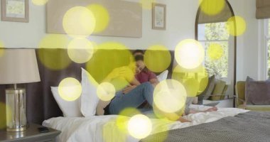 Yatak odasında teknik demo için akıllı telefon ve tablet arayüzü seçen çift. Romantik, samimiyet, rahatlama, sevecen, samimi, bağlantı, teknoloji