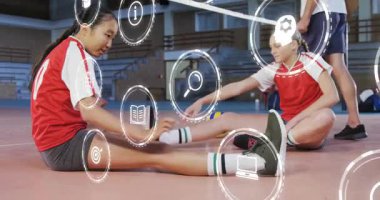 Oturan sporcular, ikonlar havada süzülürken voleybol sahasında ısınmak için bacak esnetiyorlar. Sporcular, takım çalışması, fitness, antrenman, spor, motivasyon, hareket