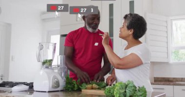 Yemek pişirirken kivi yiyen çift mutfaktan yükselen yüzen sosyal medya ikonları ateşliyor. Aşçılık, işbirliği, modern, yaşam tarzı, canlı, bağlantı, bağlılık