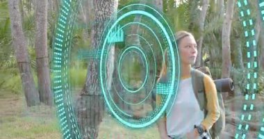 Yürüyüşçü sırt çantasındaki kayışları ayarlarken AR arayüzü de Palmiye koruluğunu tarıyor. Güçlendirilmişlik, yürüyüş, orman, açık hava, teknoloji, keşif, macera