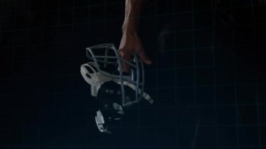 Futbol kaskını kavramış bir sporcu, duvarın üzerinden HUD kaplamasını etkinleştiriyor. Bu da teknolojiyi gösteriyor. Spor, yenilik, fütürizm, teknoloji, atletik ekipman, dijital arayüz, siber