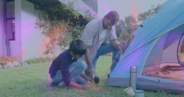 Oğlu kazığı tutarken, baba kazıkları çakıyor kamp için kubbe çadırı kuruyor. Açık hava, takım çalışması, inşaat, macera, kaynaşma, eğlence, aile