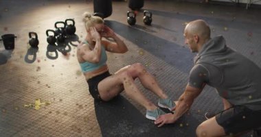 Ayak bileği tutan spor hocası. Çekirdek için kettlebell ile mekik çeken bir kadın. Egzersiz, güç, fitness, eğitim, sağlık, motivasyon, atletizm