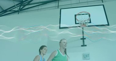 Mavi ve yeşil takımlar, pas dalgalanması sonrası basketbol çemberinin altına atlıyorlar. Eylem, takım çalışması, atletizm, spor, rekabet, enerji, fitness