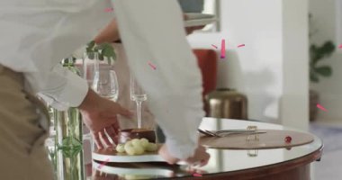 Ev sahipleri çerçeveye adım atar, kurul yerleştirir, bardakları hizalar ve konukseverlik için hediye düzenler. Misafirperverlik, zarafet, kutlama, iç mekan, sosyalleşme, düzenleme, dekor