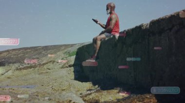 Akıllı telefonu kaldıran ve verileri kayalık kıyılardan gözden geçirmek için kaydıran bir adam. Teknolojik veriler sürükleniyor. Açık hava, teknoloji, fitness, engebeli, dijital, boş zaman, iletişim