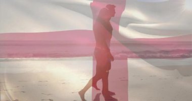 Bayrak sallanırken, kadın ve erkeğin gün batımında yürüdüğü bir seyahat reklamı. Romantik, deniz kenarı, siluet, günbatımı, birlik, uyum, sükunet