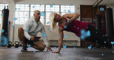 Eğitmen tıkırdatma tableti istemcisi form kontrolü için yan tahtaya dönüyor, sağlık simgeleri ortaya çıkıyor. Fitness, strength, education, wellness, determination, modern, activity