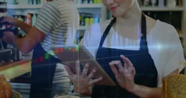 Barista sepetin üzerinden tableti kaldırıyor ve iş arkadaşı olarak kahve yaparken mali tabloları örtüyor. Teknoloji, takım çalışması, üretkenlik, modern, çalışma alanı, işbirliği, veri odaklı