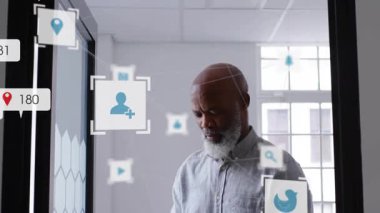 Ofis penceresinden akıllı telefonları dinleyen ve camların etrafında sosyal medya metrik simgelerini çarpan bir adam. Profesyonel, dijital, minimalist, teknoloji, iletişim, ağ, iş