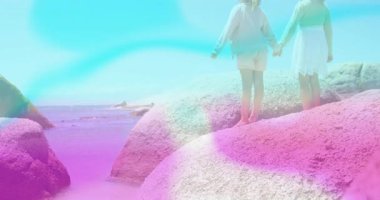 Kız kardeşler kayanın üzerinde duruyor, sol kız kardeş kollarını kaldırıyor ve seyahat için pastel alevlerle işaret ediyor. Macera, arkadaşlık, keşif, doğa, dinginlik, gençlik, canlılık