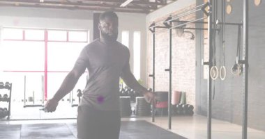 Erkek sporcu, paspasın üzerinde ip atlıyor ve parçacıklar sürüklenirken kardiyo için zıplıyor. Fitness, dayanıklılık, hareket, eğitim, sanayi, canlılık, kararlılık