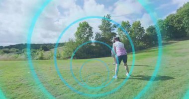 Topun arkasında kadın bükme kulübü ve golf antrenmanı için mavi daireler çizerken erkek gözlem yapıyor. Golf, boş zaman, açık hava, aktivite, koçluk, fitness, doğa