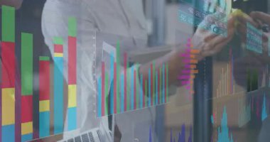 Meslektaşlar cam ekranda dizüstü bilgisayarı eğip çizelgeleri analiz ediyor ve planlama için yapışkan notlar yerleştiriyorlar. İşbirliği, beyin fırtınası, veri görselleştirme, strateji, planlama, modern çalışma alanı